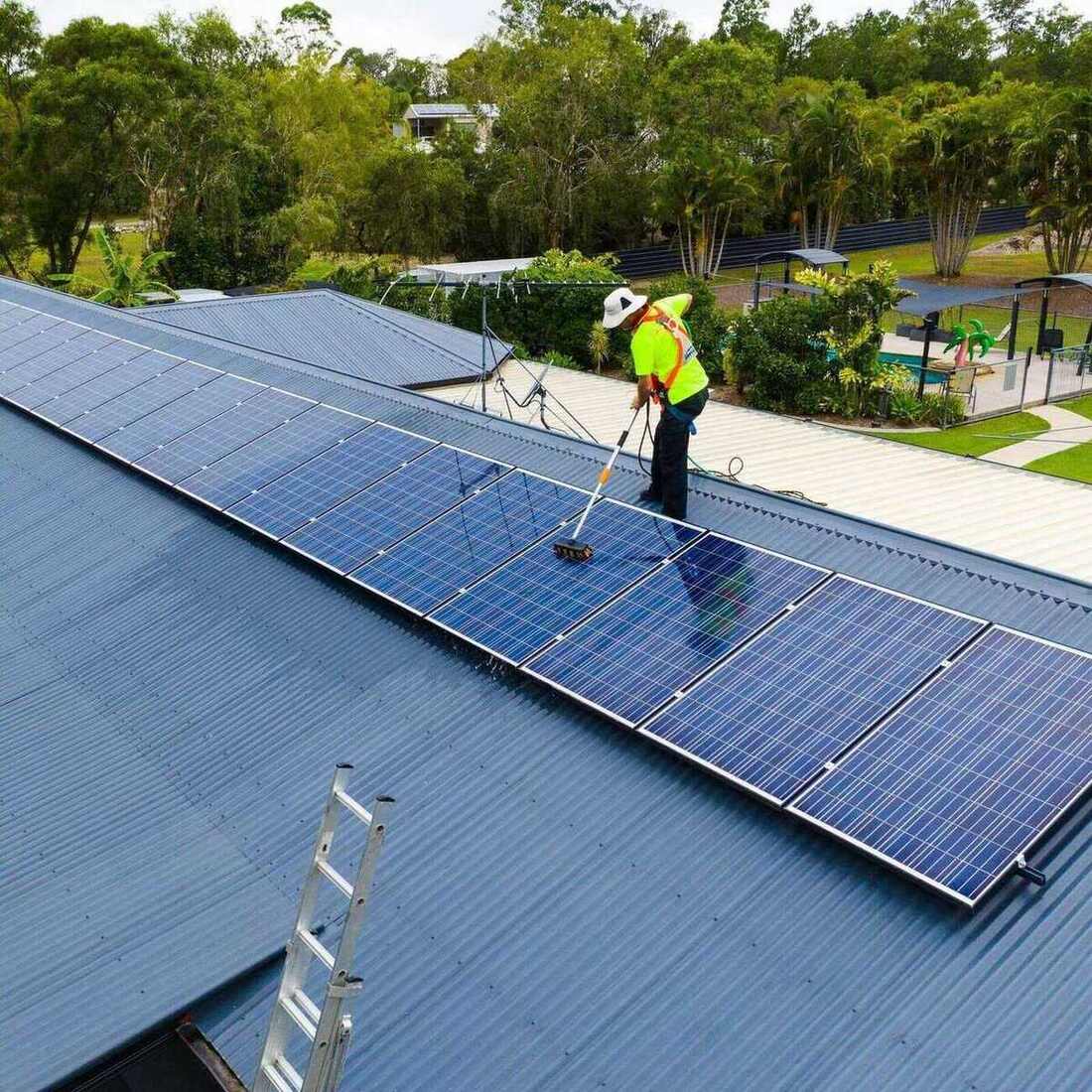 Solar panels on residential roof being cleaned by professionals